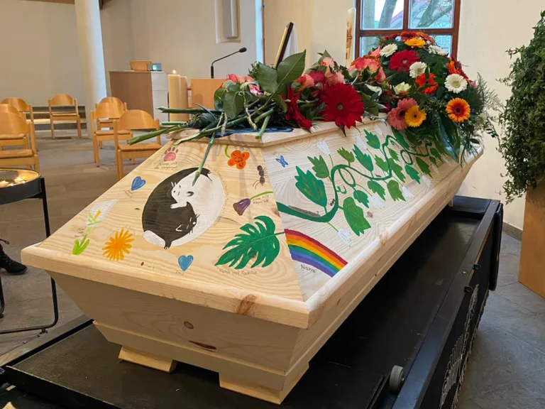 Bemalter Holzsarg mit Deko bei der Trauerfeier